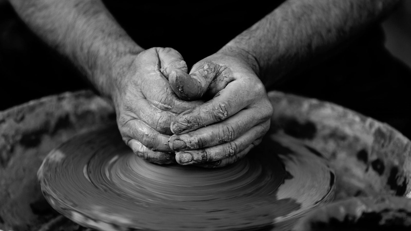 A potter's hands shaping wet clay on a spinning wheel