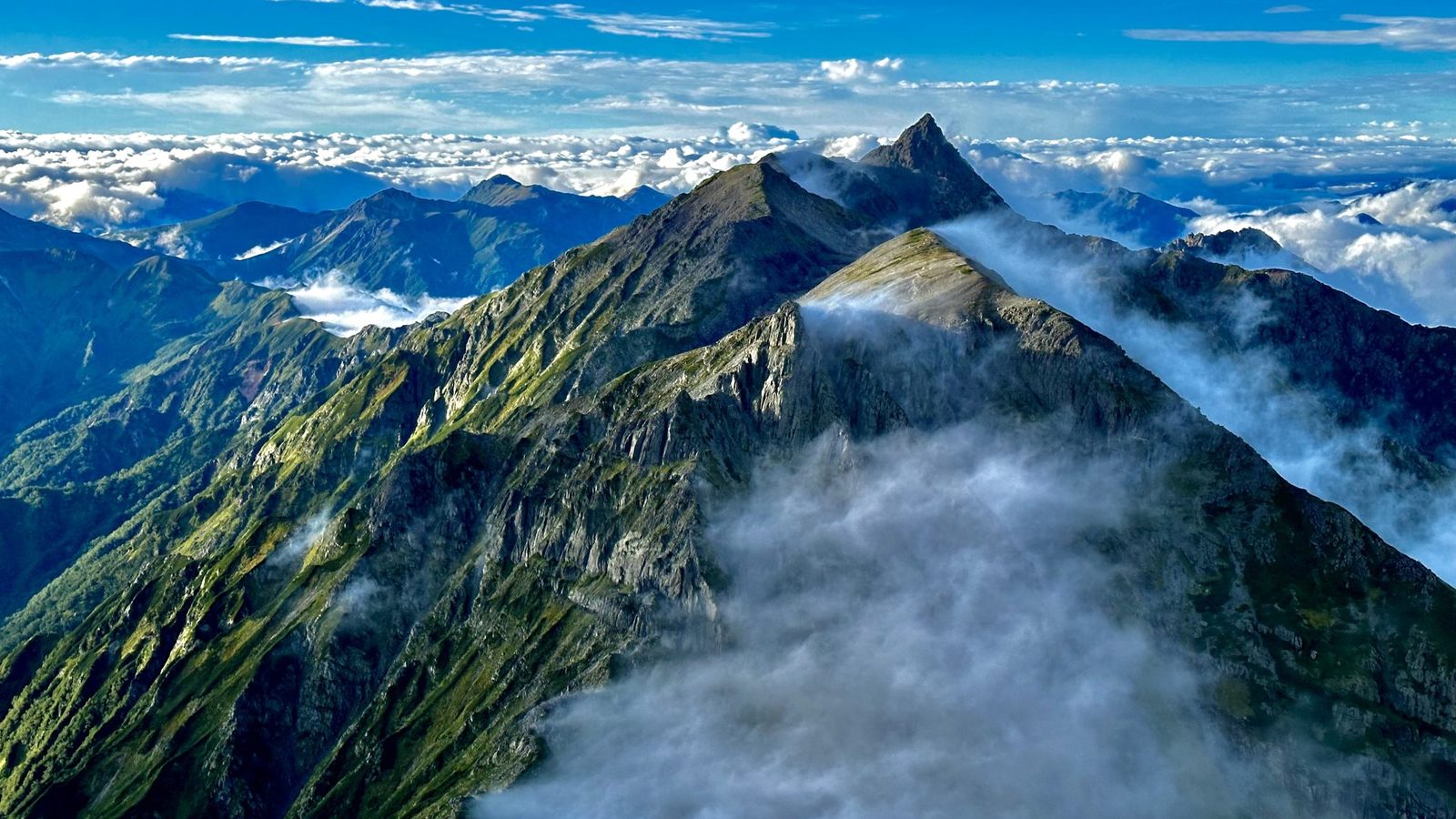 A mountain ridge rising above the clouds at sunrise